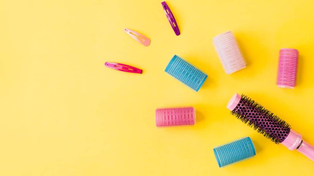 Escova e bobes de cabelo em um fundo amarelo.