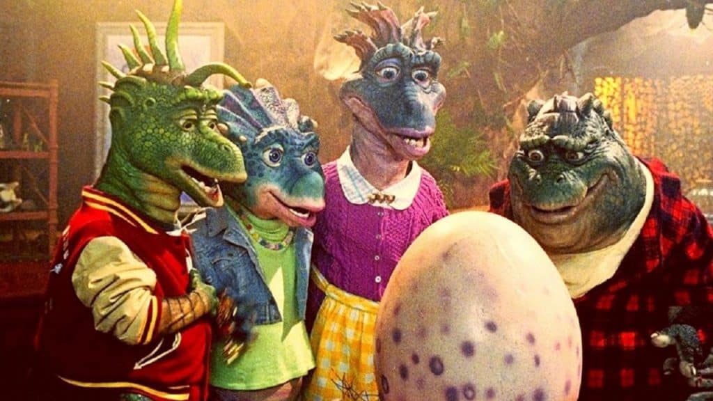 Personagens de Família Dinossauros olhando para um ovo.