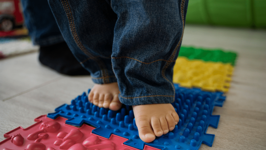 Pé de uma criança pisando em um tapete sensorial