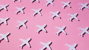 Aviões de papel em fundo rosa representando o jet lag.