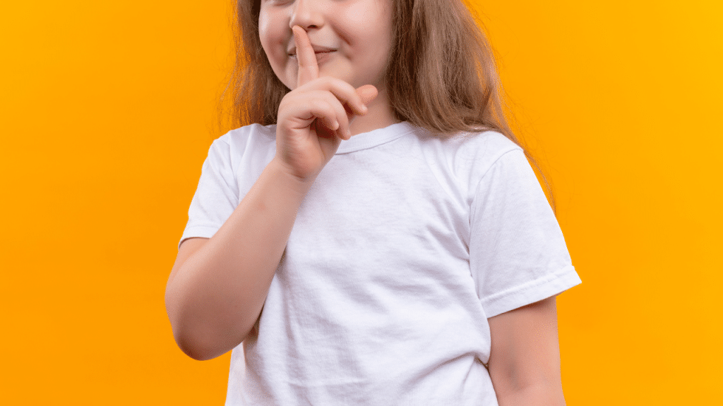 Criança com o dedo na boca e um fundo laranja