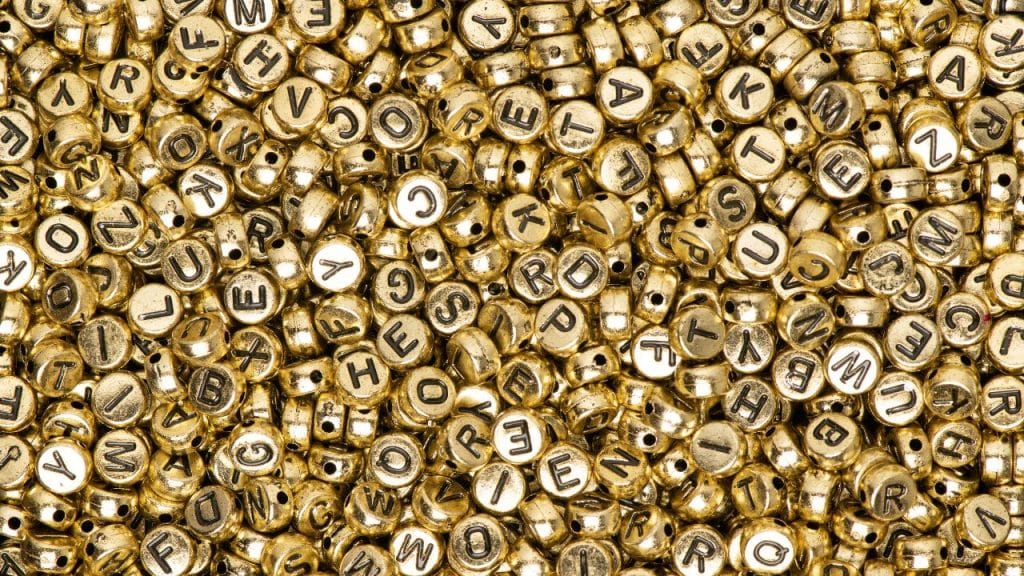 Miçangas douradas representando nomes de bebê.