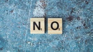 Letras de madeira formando a palavra "no", representando a disciplina de um filho.