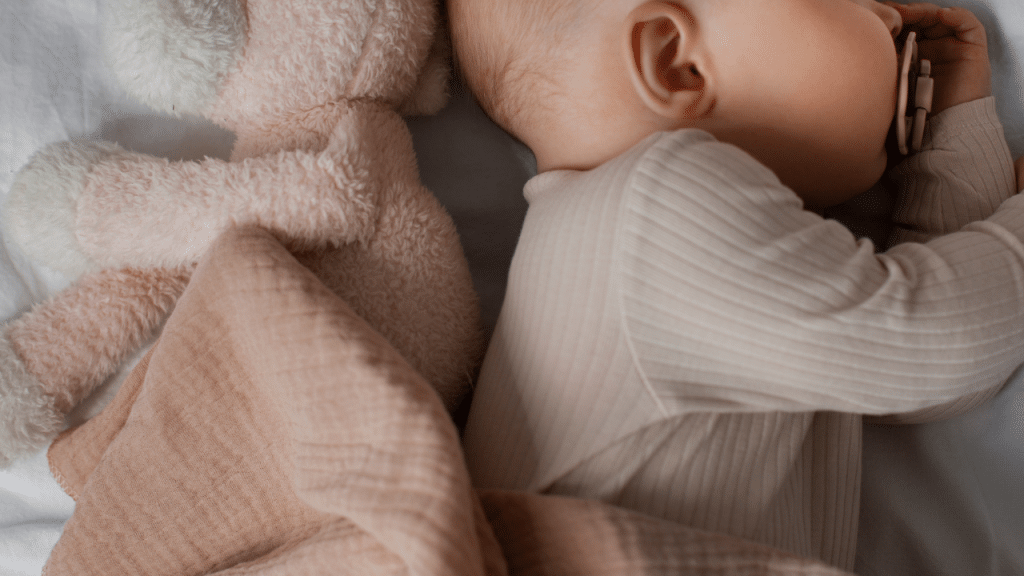Criança dormindo ao lado de um ursinho de pelucia