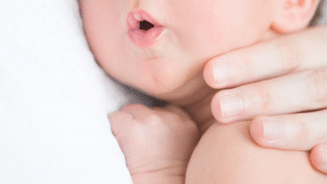 Criança deitada no colo da mãe com a boca aberta