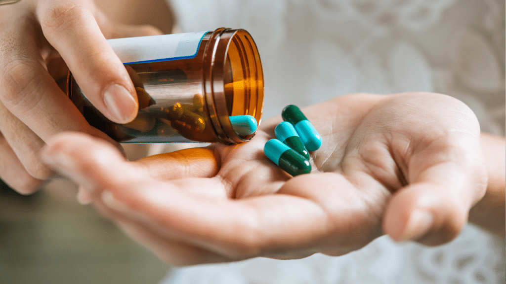 Mão de mulher derramando pilias de rémedio em sua outra mão