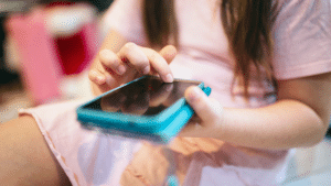 criança com um celular na mão com uma capinha azul