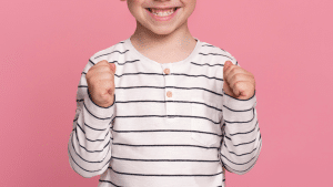 Sorrios de uma criança (menino), com uma camisa listrada e um fundo rosa