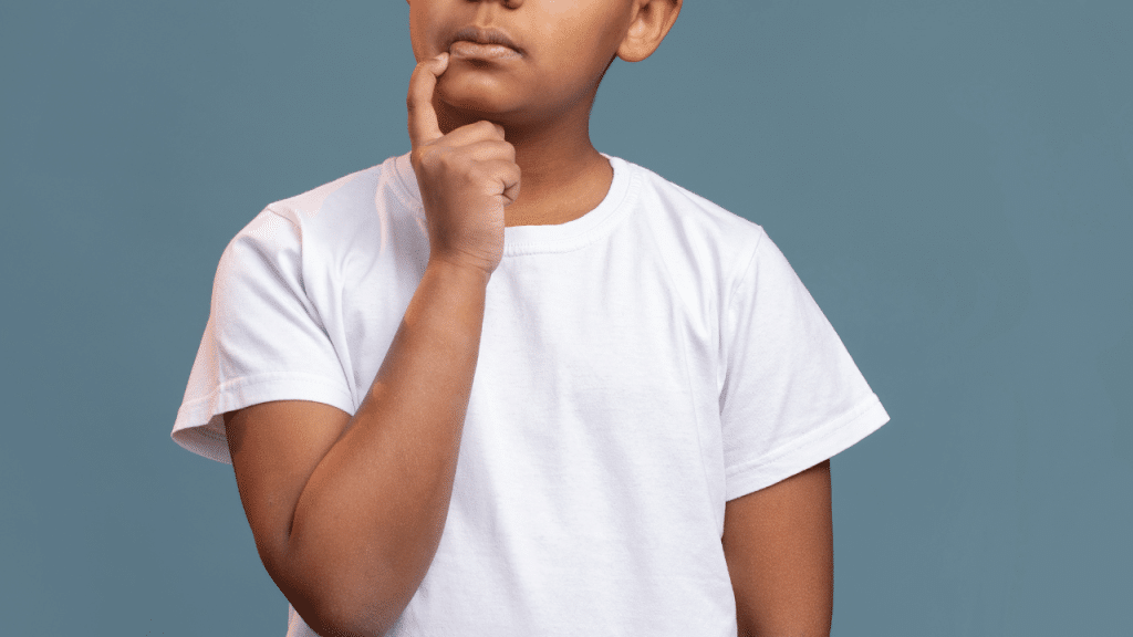 Criança com a mão ma boca, uma camisa branca e um fundo verde