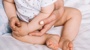 Bebê segurando a barriga, aparentemente com dores intestinais.