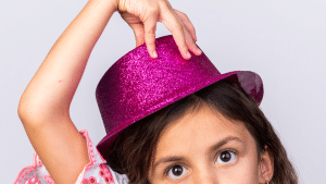 Criança com um chapéu rosa e com a mão encima dele