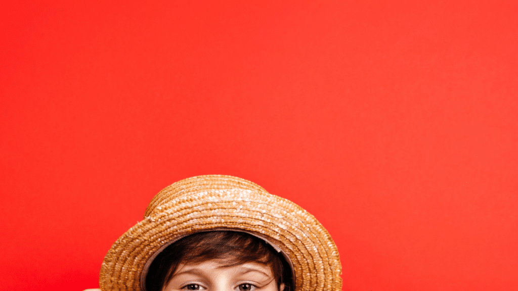 Criança com um chapéu e o fundo da foto é laranja