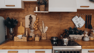 Uma cozinha completa com fogão, ármario, tábua de carne, alhos pendurados, panela encima do fogão