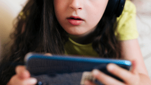 Criança de fone jogando no celular