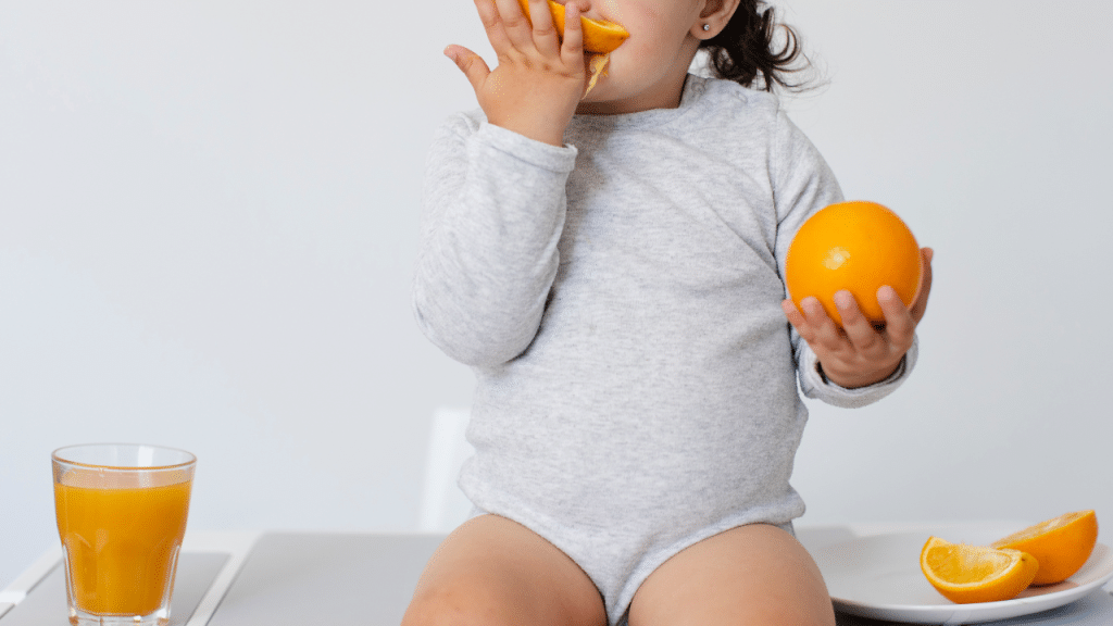 Criança chupando uma laranja