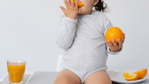 Criança chupando uma laranja