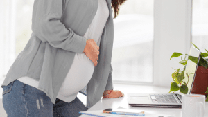 mulher com cólica, apoiando o braço em uma mesa