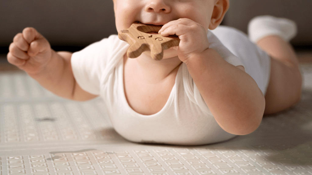 Bebê com um macaquinho branco e um brinquedo com a mão na boca