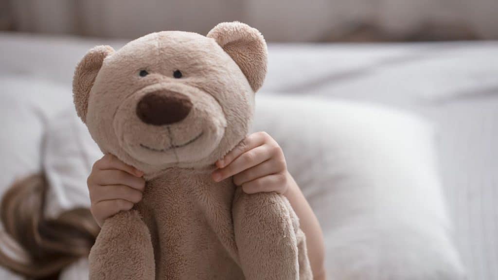 Criança com urso de pelúcia representando a parentalidade intensiva.