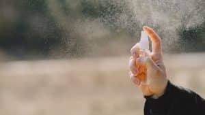 Pessoa espirrando repelente de insetos no ar.