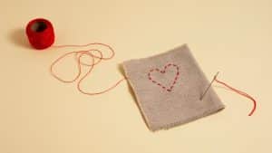 Tecido costurado com linha vermelha representando a infecção pós-cesariana.