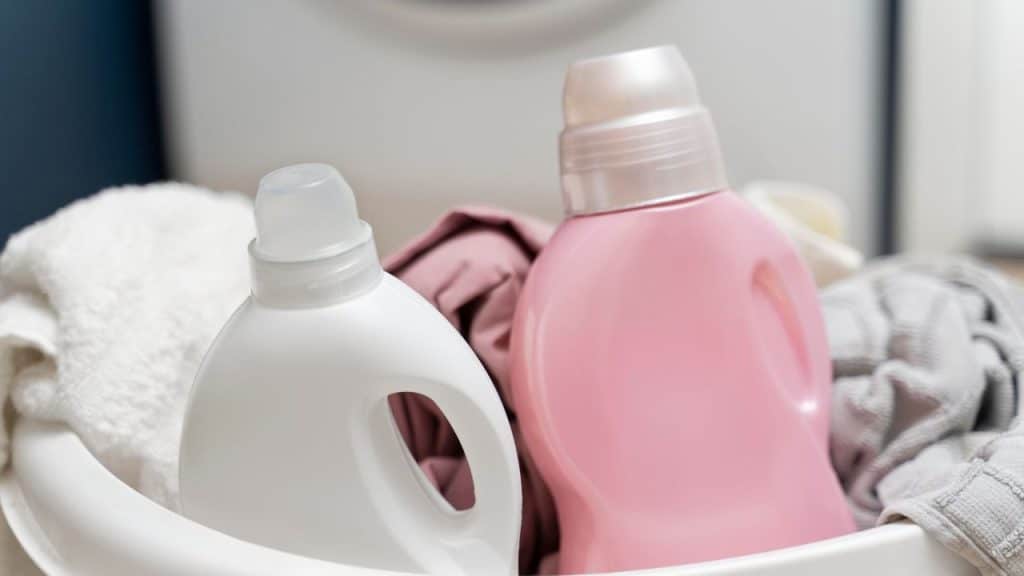 Amaciante de roupa em embalagem branca e rosa dentro de uma bacia.