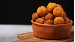 Bolinho de arroz em tigela marrom em frente a um fundo preto.