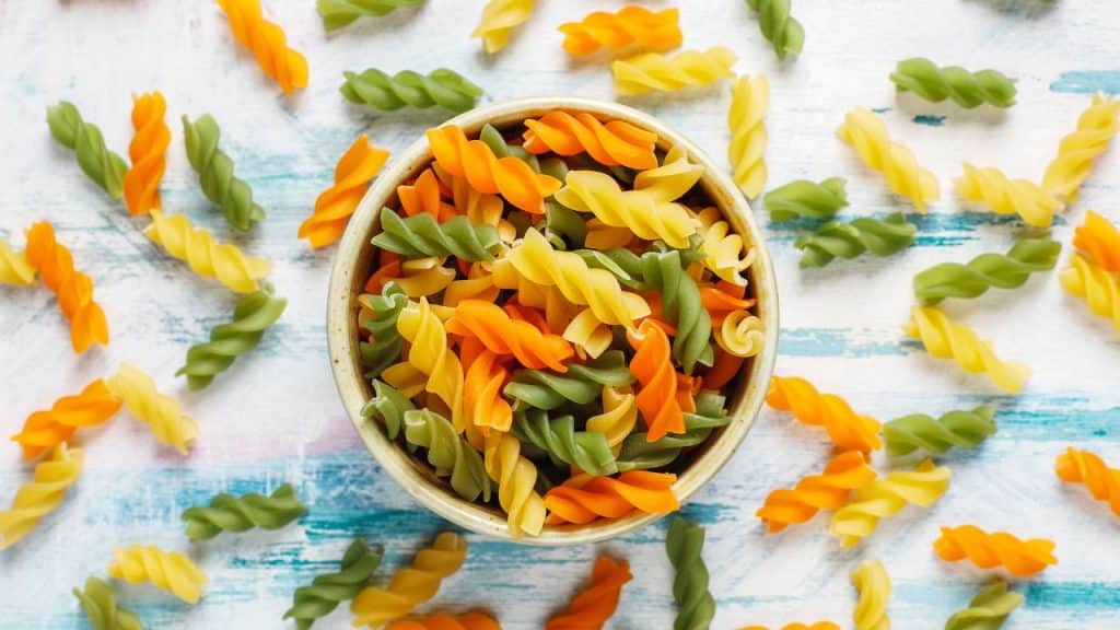 Macarrão salada em uma tigela com macarrões em volta.