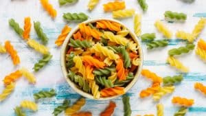 Macarrão salada em uma tigela com macarrões em volta.