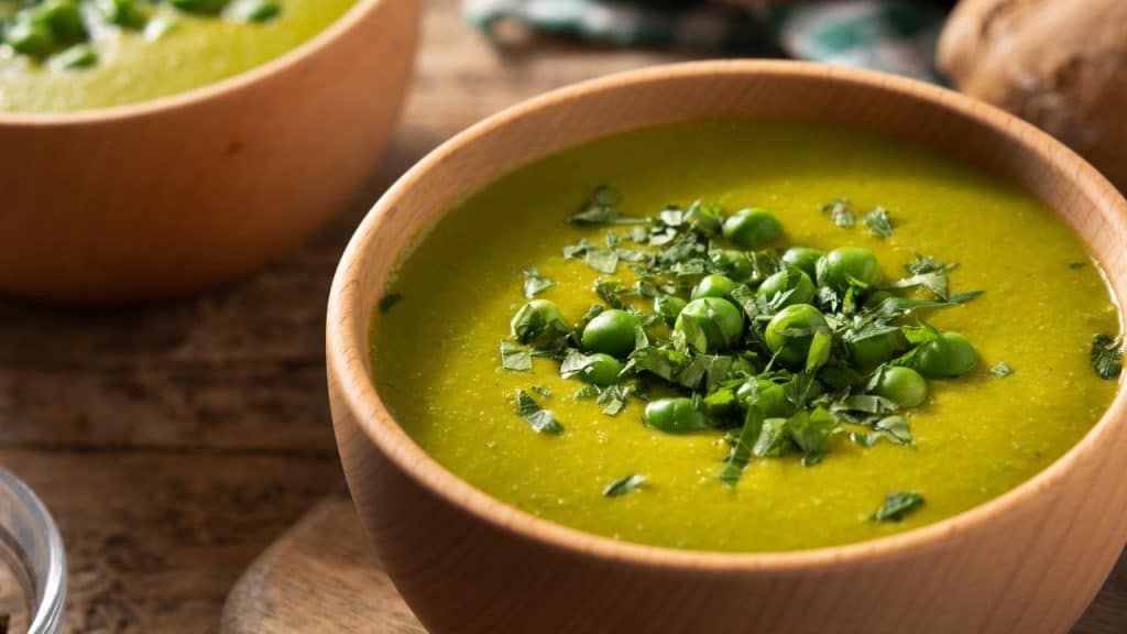 Sopa de ervilha em uma tigela marrom.