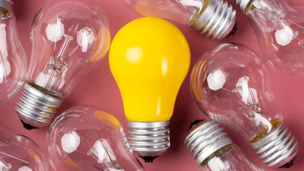 Lâmpada colorida no meio de lâmpadas transparentes representando um superdotado.