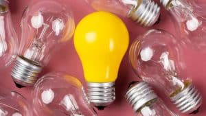 Lâmpada colorida no meio de lâmpadas transparentes representando um superdotado.