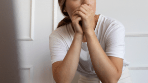 Mulher com a mão na boca aparentemente apreensiva.