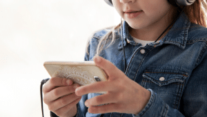 Criança mexendo no celular com um fone de ouvido