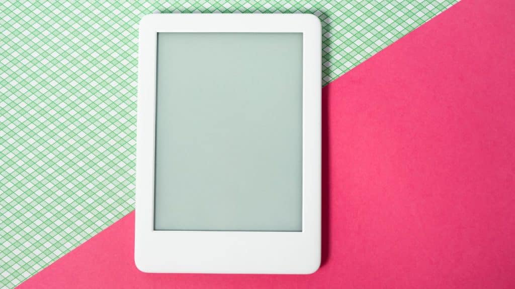 Aparelho eletrônico em fundo azul e rosa representando o uso de telas na infância.