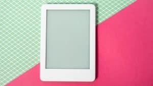 Aparelho eletrônico em fundo azul e rosa representando o uso de telas na infância.