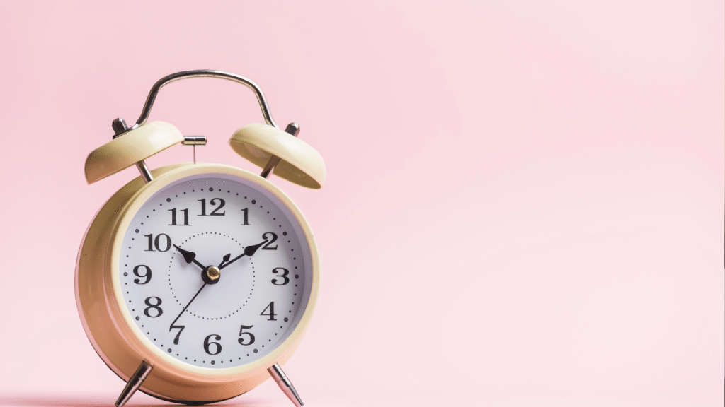 Foto de um relógio branco em um findo rosa