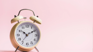 Foto de um relógio branco em um findo rosa