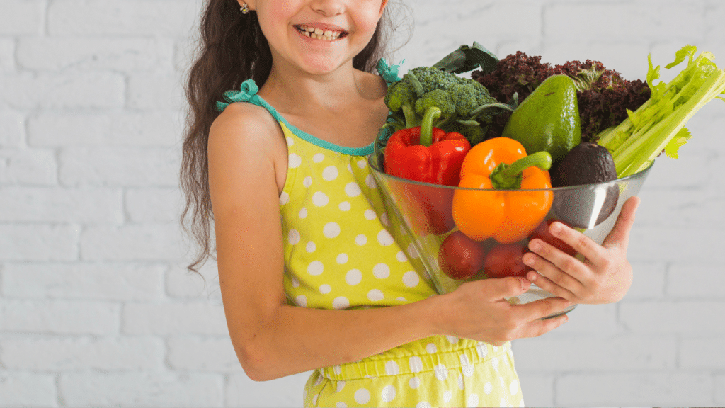 Criança segurando uma bandeja cheia de verduras